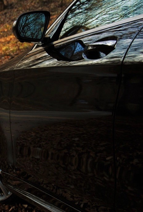De spiegel en het portier van een donkere auto, van dichtbij gefotografeerd