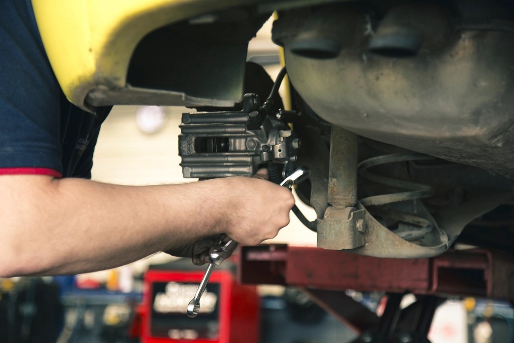 Een monteur werkt aan de onderkant van een auto in de werkplaats